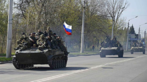 A group of military tanks driving down a street Description automatically generated with low confidence