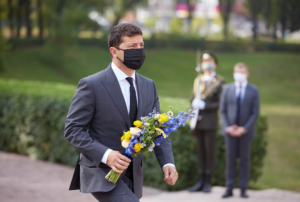 A person in a mask holding flowers Description automatically generated with medium confidence