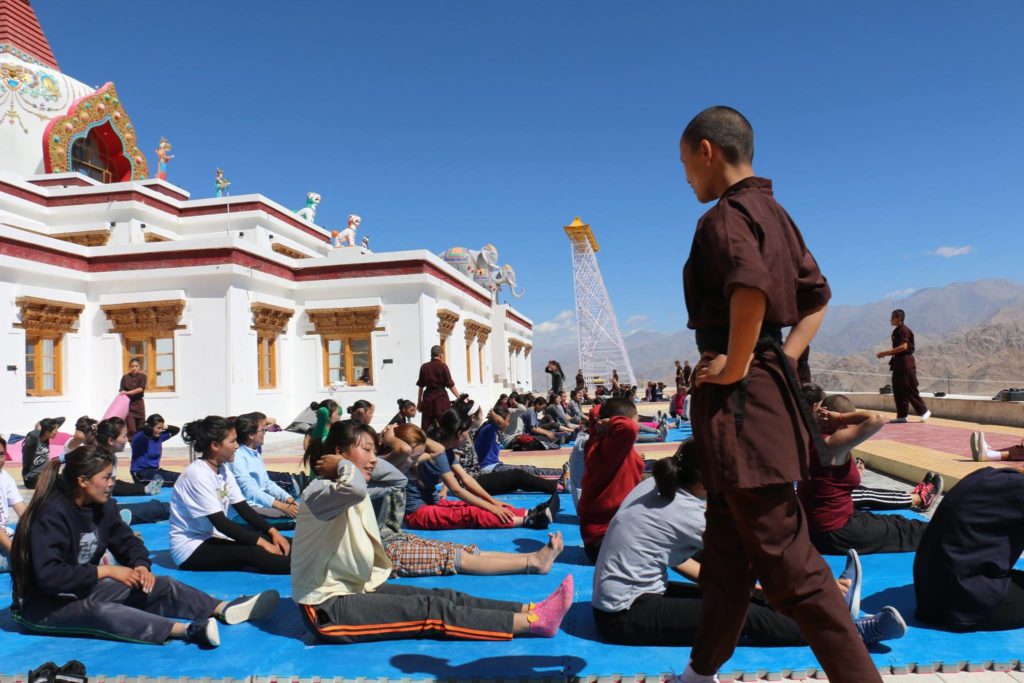 A person standing in front of a group of people sitting on the groundDescription automatically generated with medium confidence