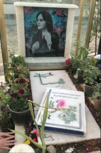 A grave with a picture of a person and flowersDescription automatically generated