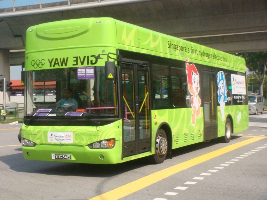 A green bus on the streetDescription automatically generated