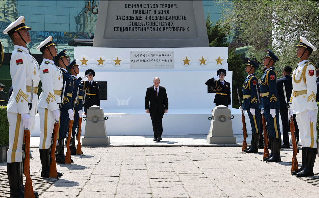 A person in a suit standing in front of a group of soldiersDescription automatically generated