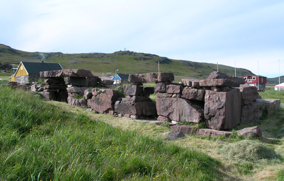 A large rock wall in a grassy fieldDescription automatically generated