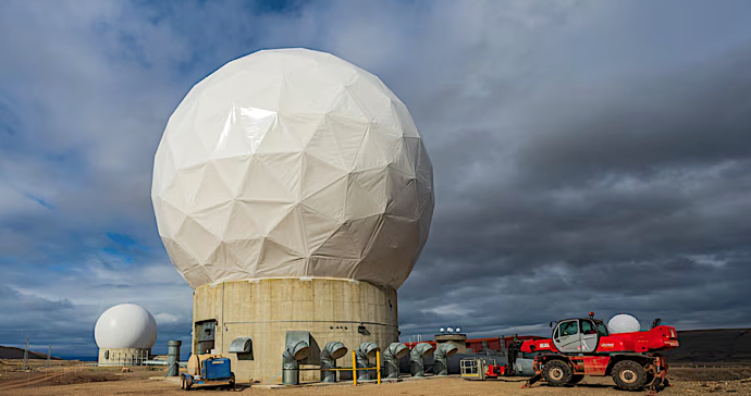 A large white dome with a tractor in the backgroundDescription automatically generated