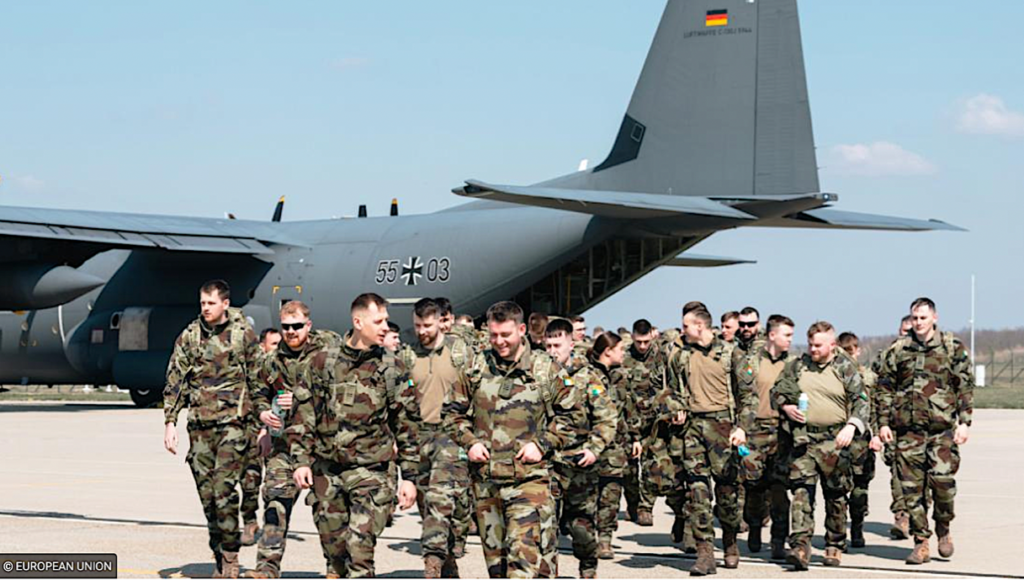 A group of people in military uniforms walking in front of an airplaneDescription automatically generated