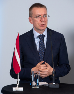 A person in a suit and tie standing in front of a microphoneDescription automatically generated