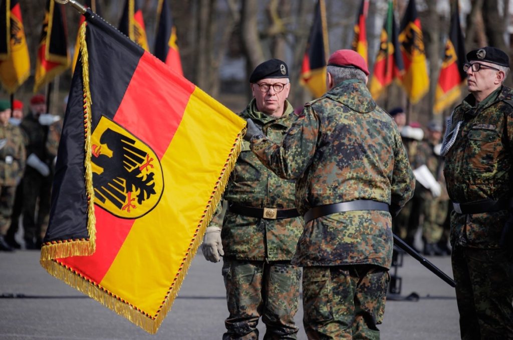A person in military uniform holding a flagDescription automatically generated