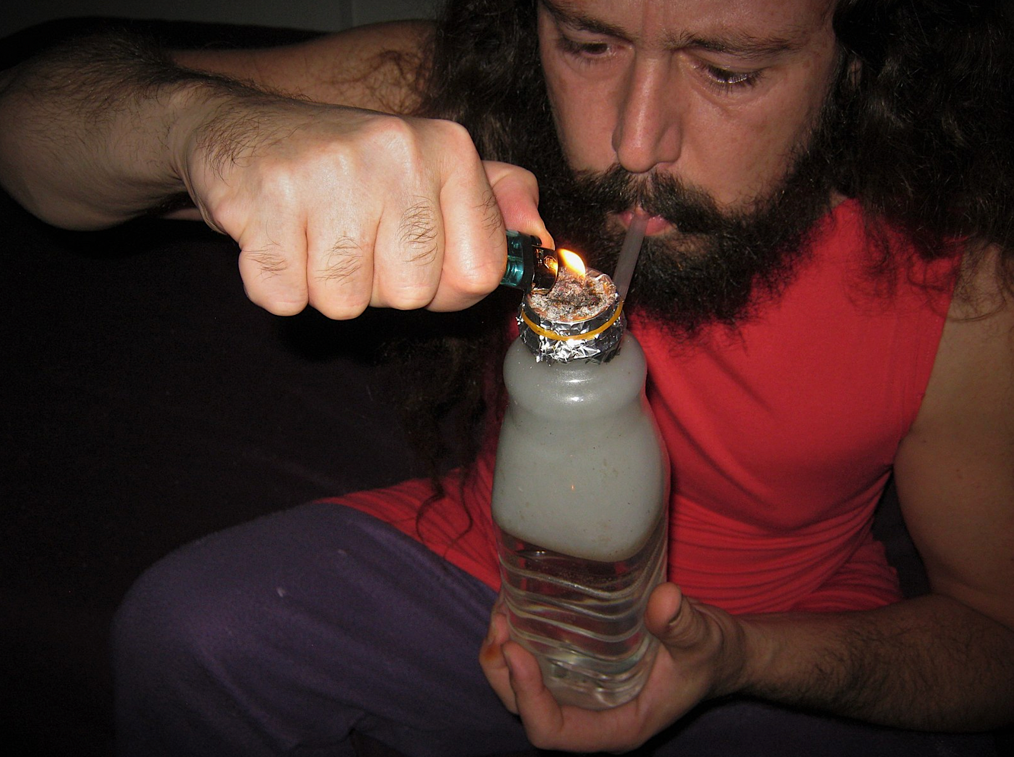 A person lighting a bottle with a lighterDescription automatically generated