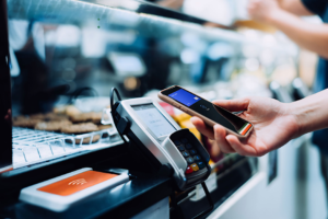 A person using a phone to pay for a payment Description automatically generated