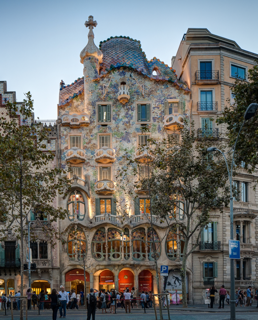 Casa Batlló with many windows and a lot of treesDescription automatically generated