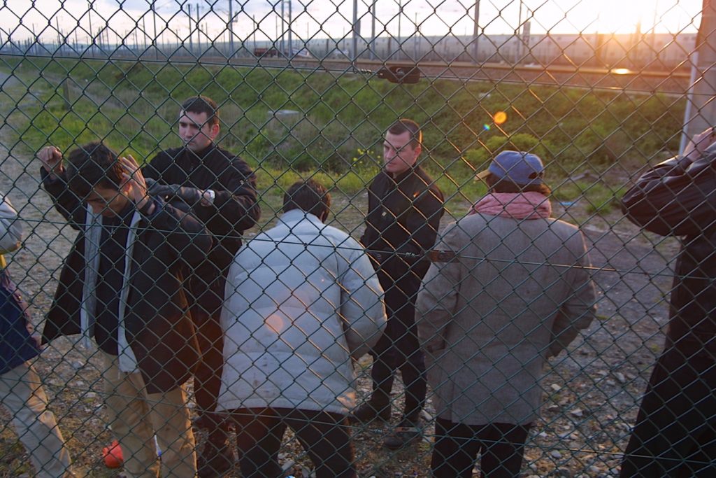 A group of people standing behind a fenceDescription automatically generated