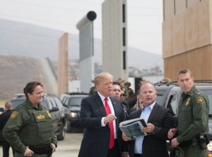 A person in a suit and tie standing next to a group of peopleDescription automatically generated