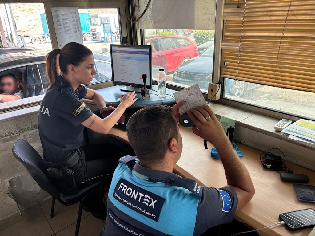 A person sitting at a desk with a person in front of a computerDescription automatically generated