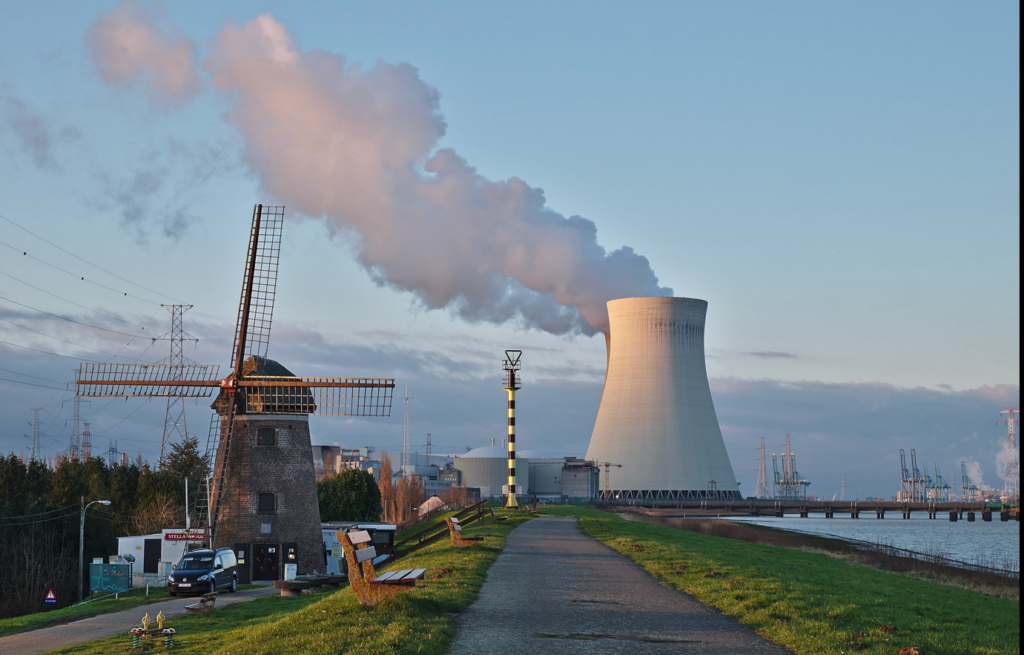A windmill next to a factoryDescription automatically generated